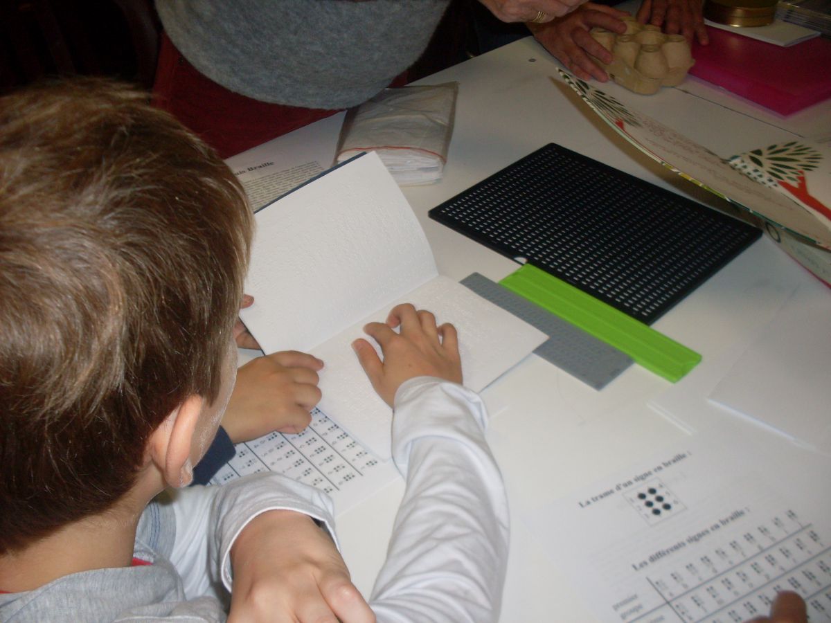 Atelier Braille, un élève passe son index sur le texte en braille